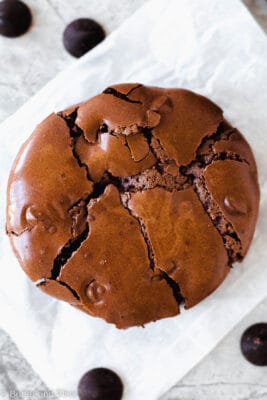 Single flourless chocolate cookie on a piece of parchment paper.