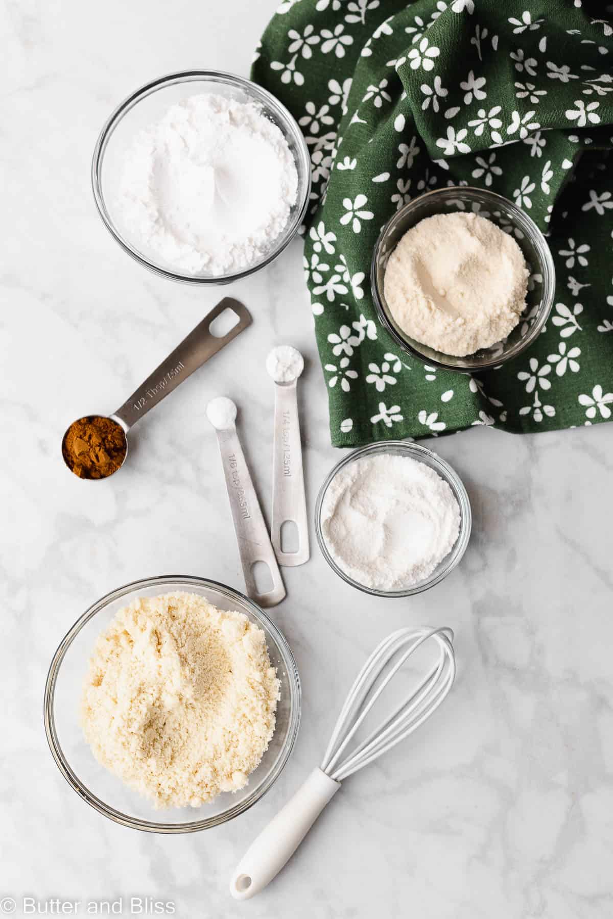 Dry ingredients for apple cupcakes in glass bowls on a table.