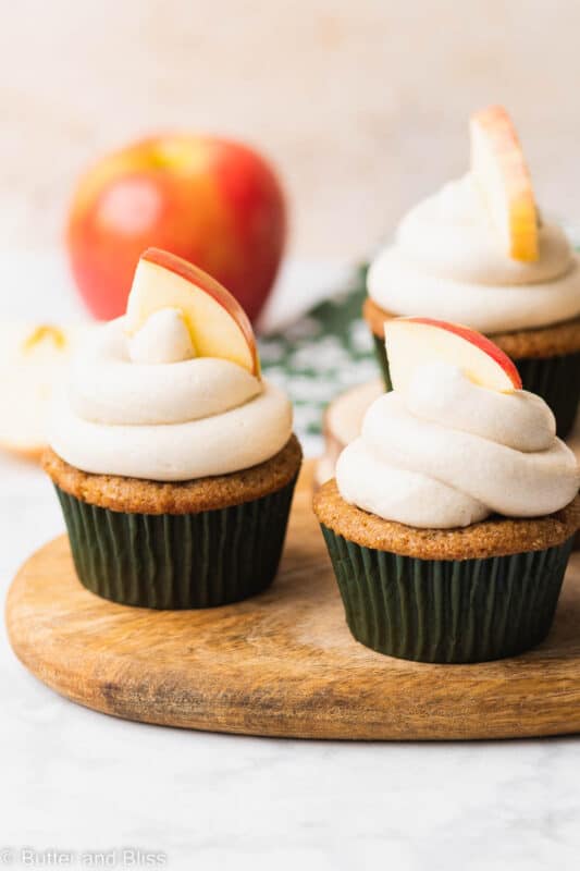 Two frosted apple spice gluten free cupcakes on a wood tray.