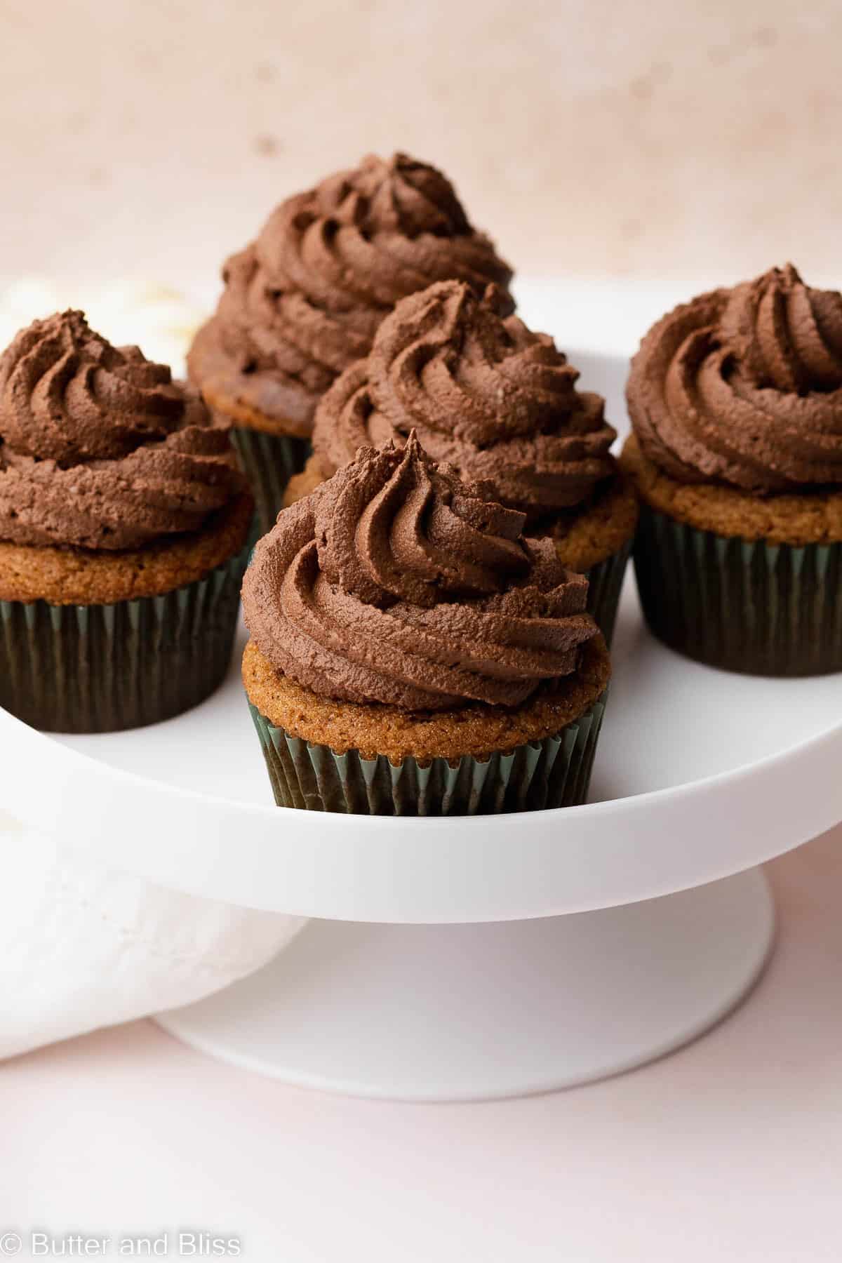 Plate of pumpkin cupcakes topped with whipped chocolate frosting.