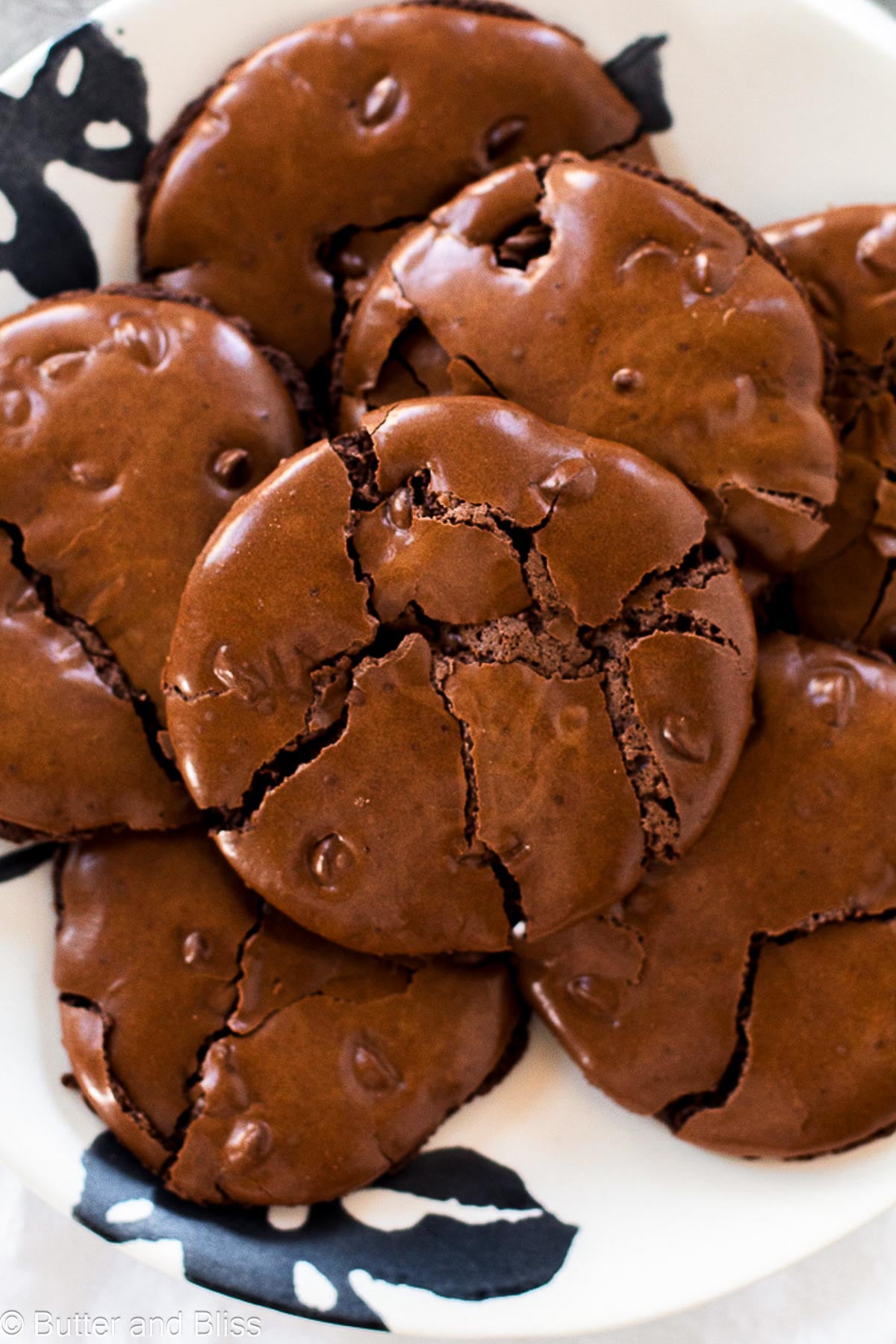 A plate of flourless chocolate cookies with crackly brownie tops.