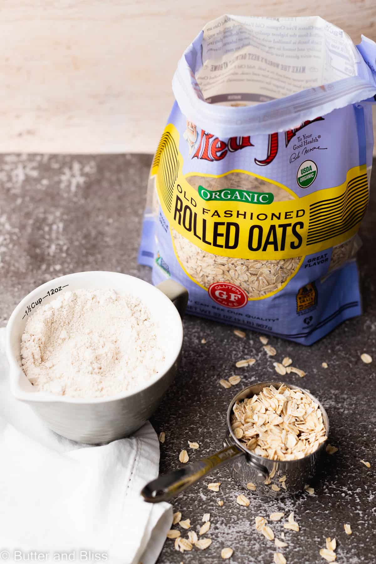 Rolled oats in a bag with a bowl of oat flour next to it.