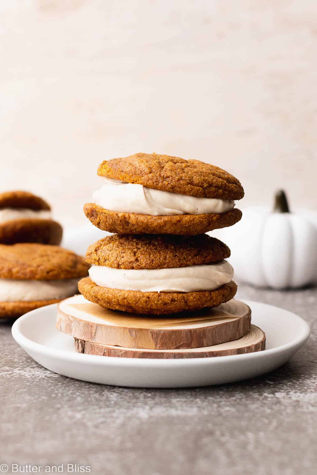 Two gluten free pumpkin spice whoopie pies stacked on a plate.