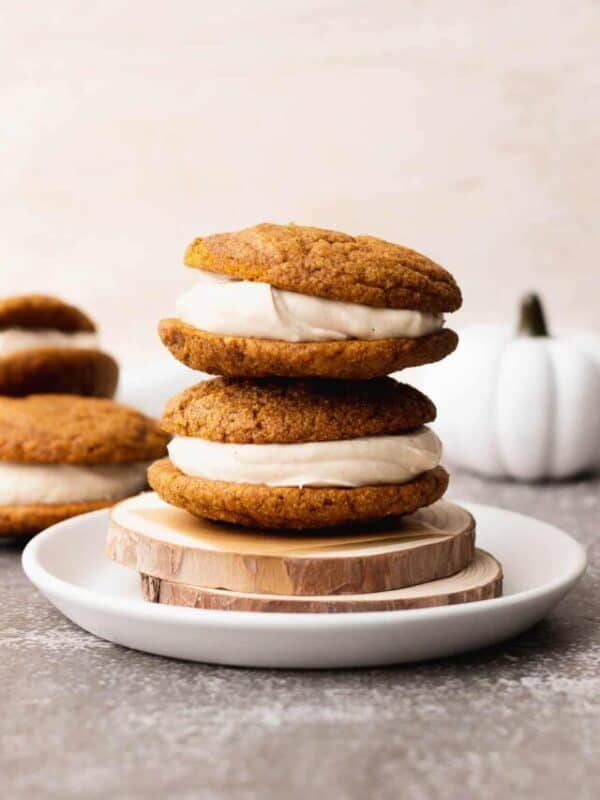 Two gluten free pumpkin spice whoopie pies stacked on a plate.