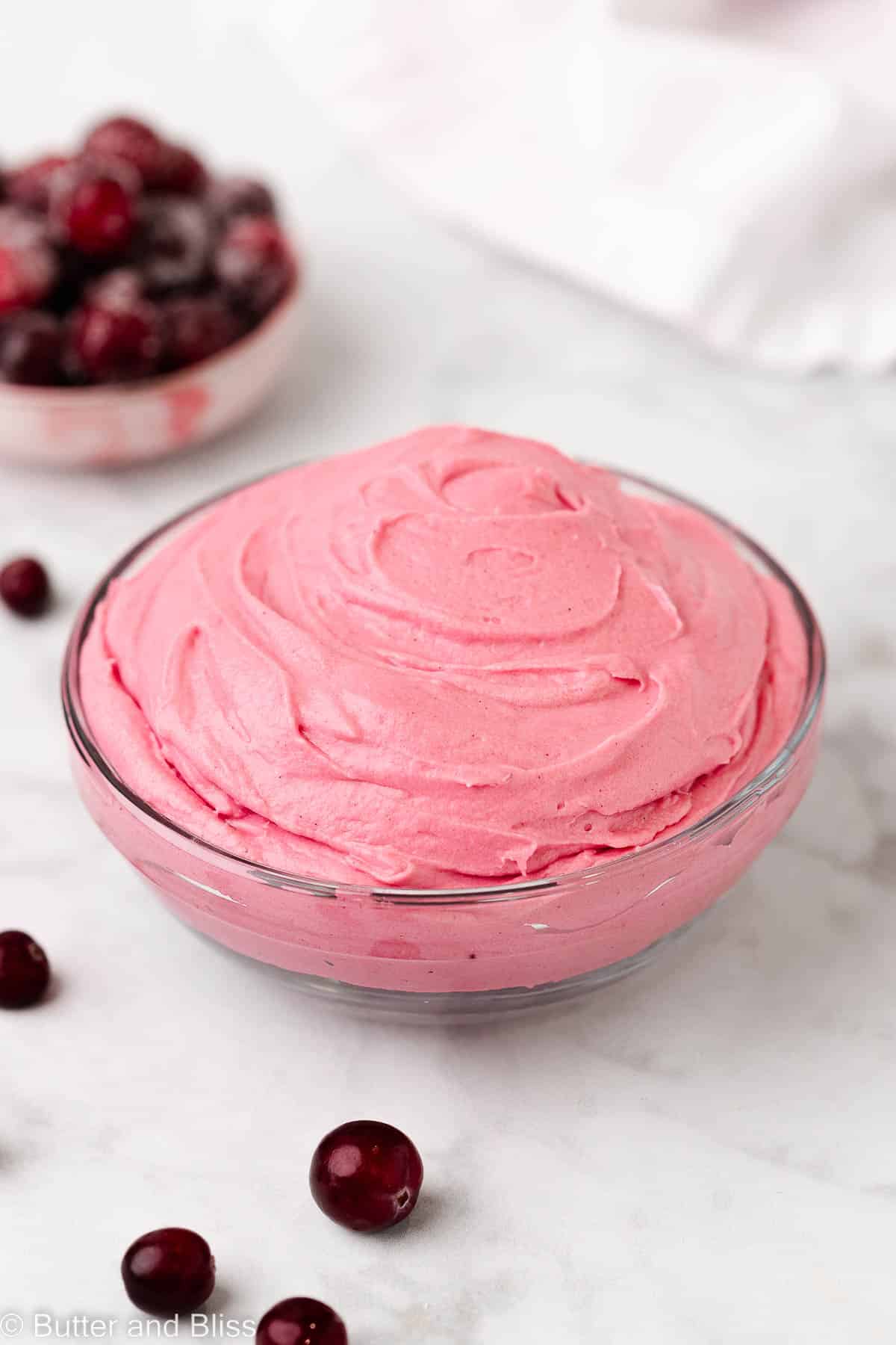 Bowl of cranberry buttercream set on a table.