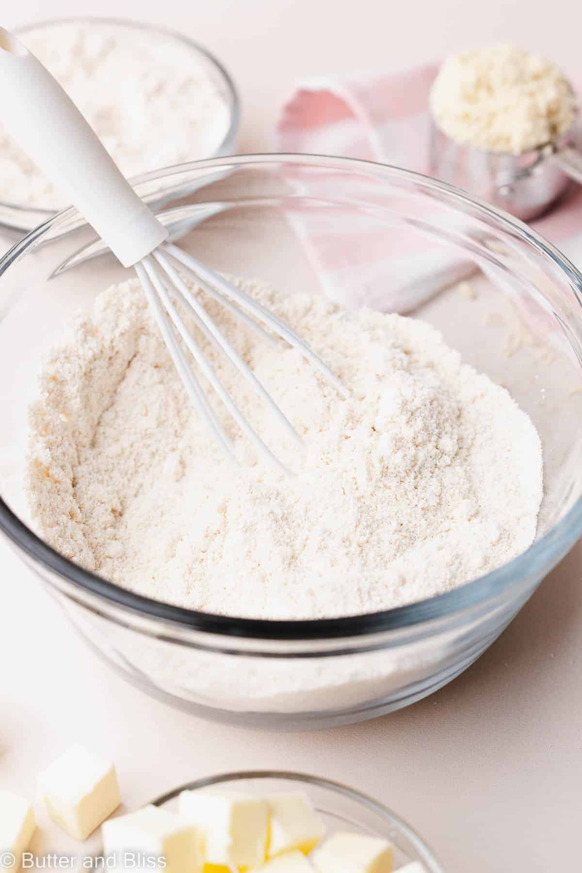 Bowl of gluten free flour mix with a white whisk.