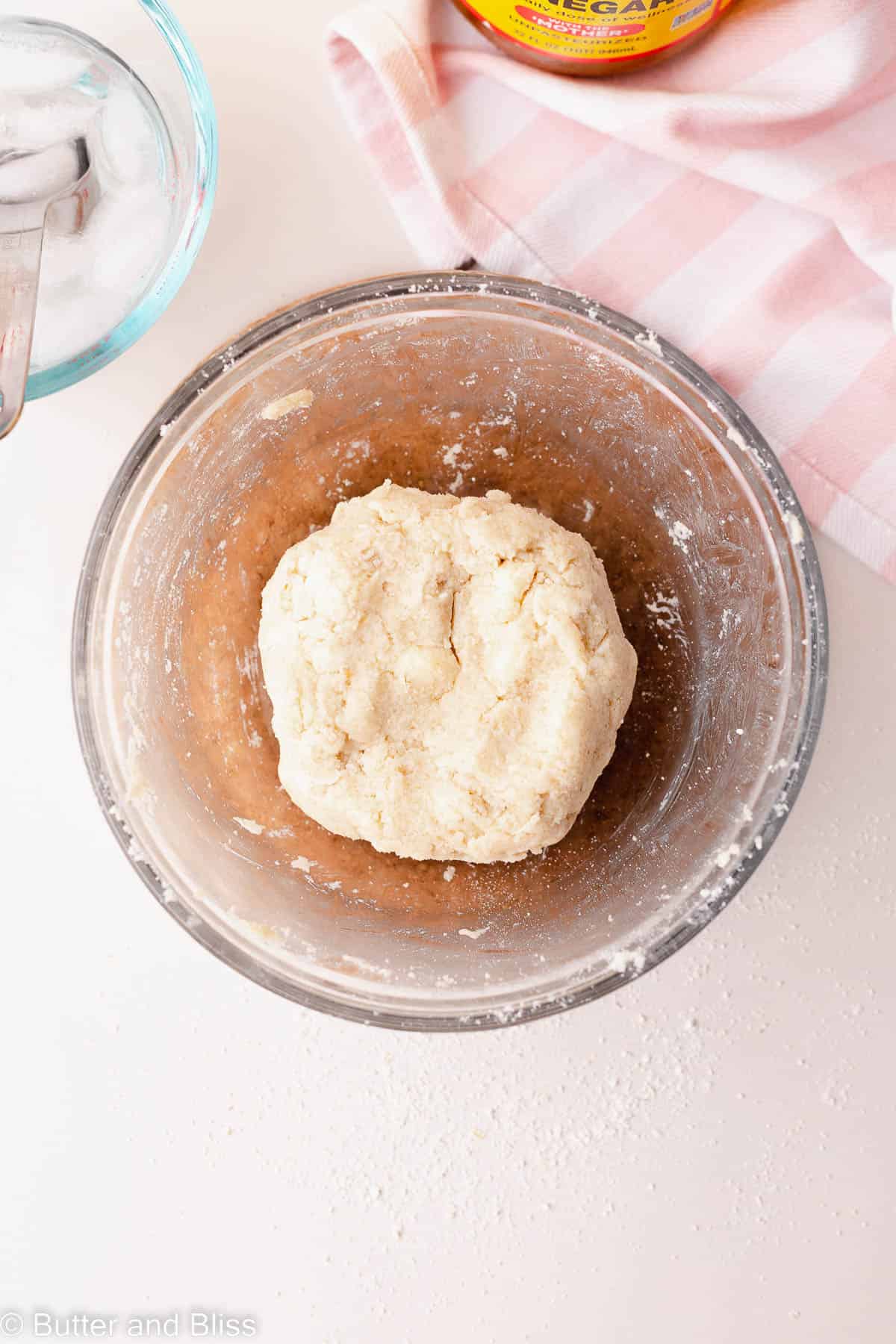 Pie dough dough formed into a ball in a glass bowl.