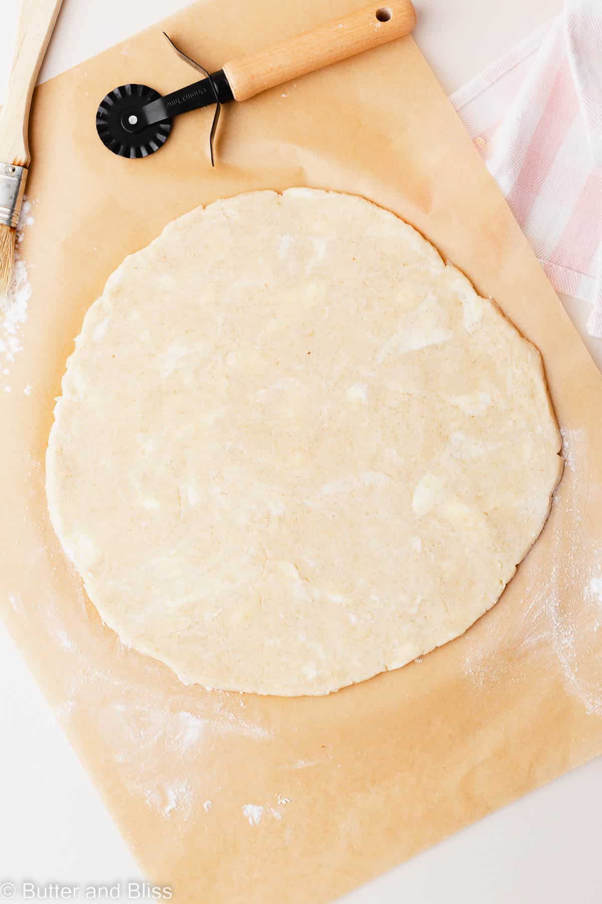 Rolled out gluten free pie crust on a piece of parchment paper.