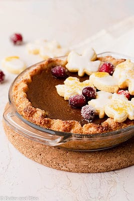 Gluten free pumpkin pie decorated with edible fall decor in a small glass pie dish.