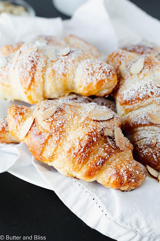 A basket of homemade almond croissants dusted with powdered sugar.