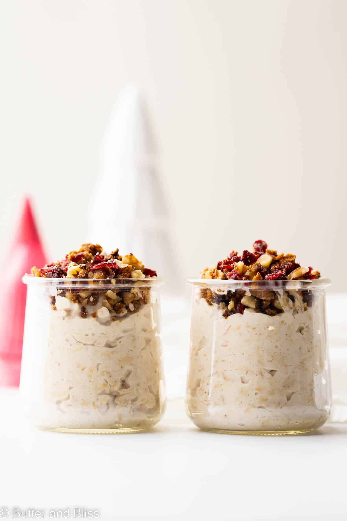 Dairy free eggnog overnight oats in small serving glasses set on a white table.