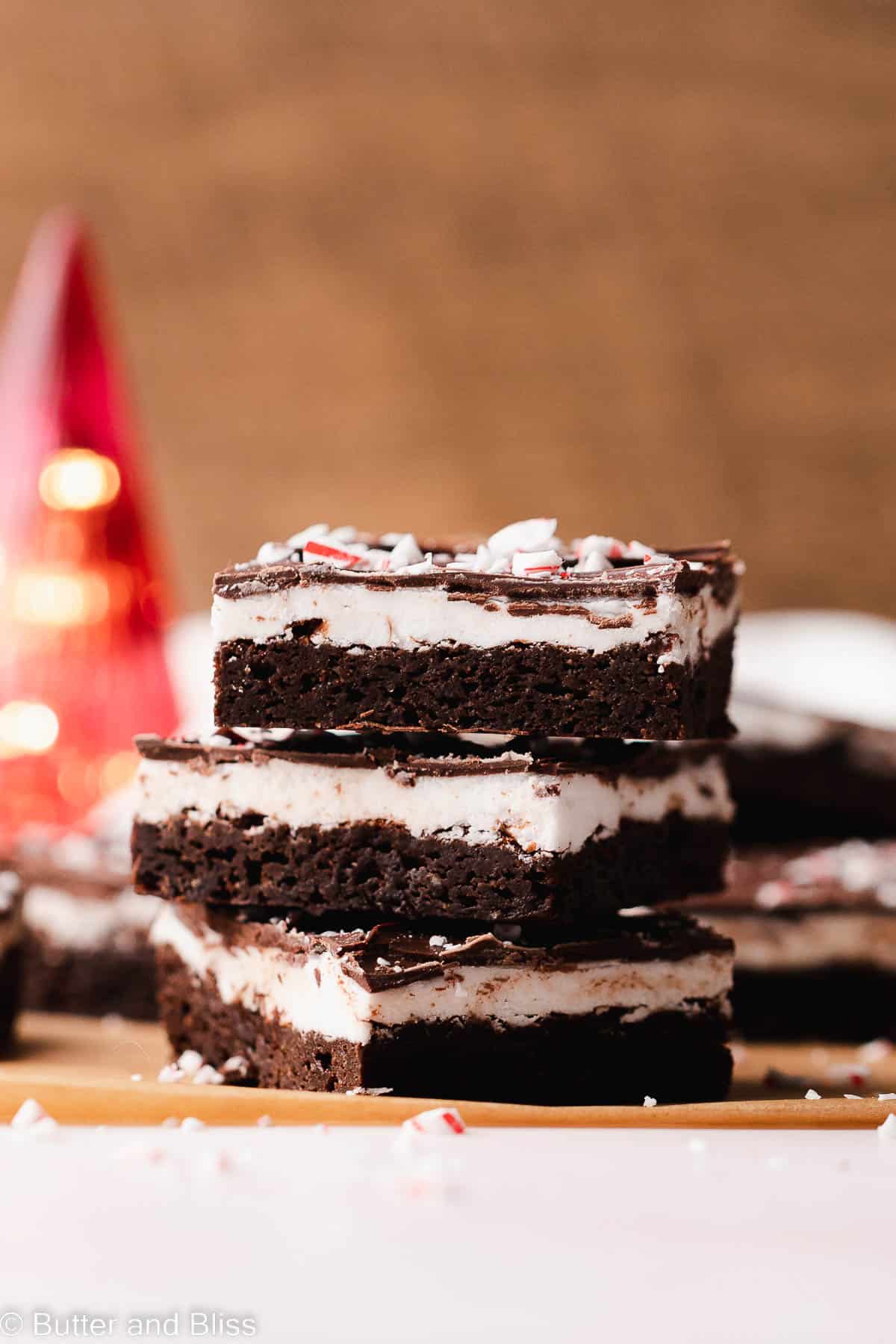 Small lopsided stack of gluten free peppermint patty brownies with candy cane sprinkles.