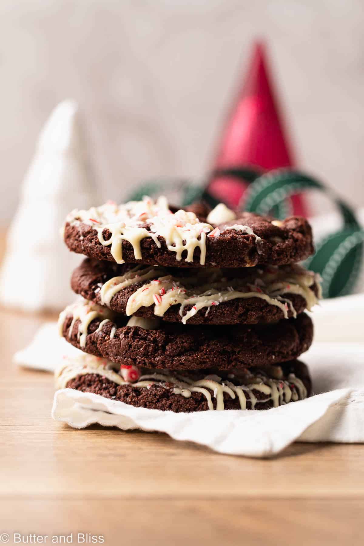 A neat stack of chocolate gluten free peppermint cookies with white chips and drizzle.