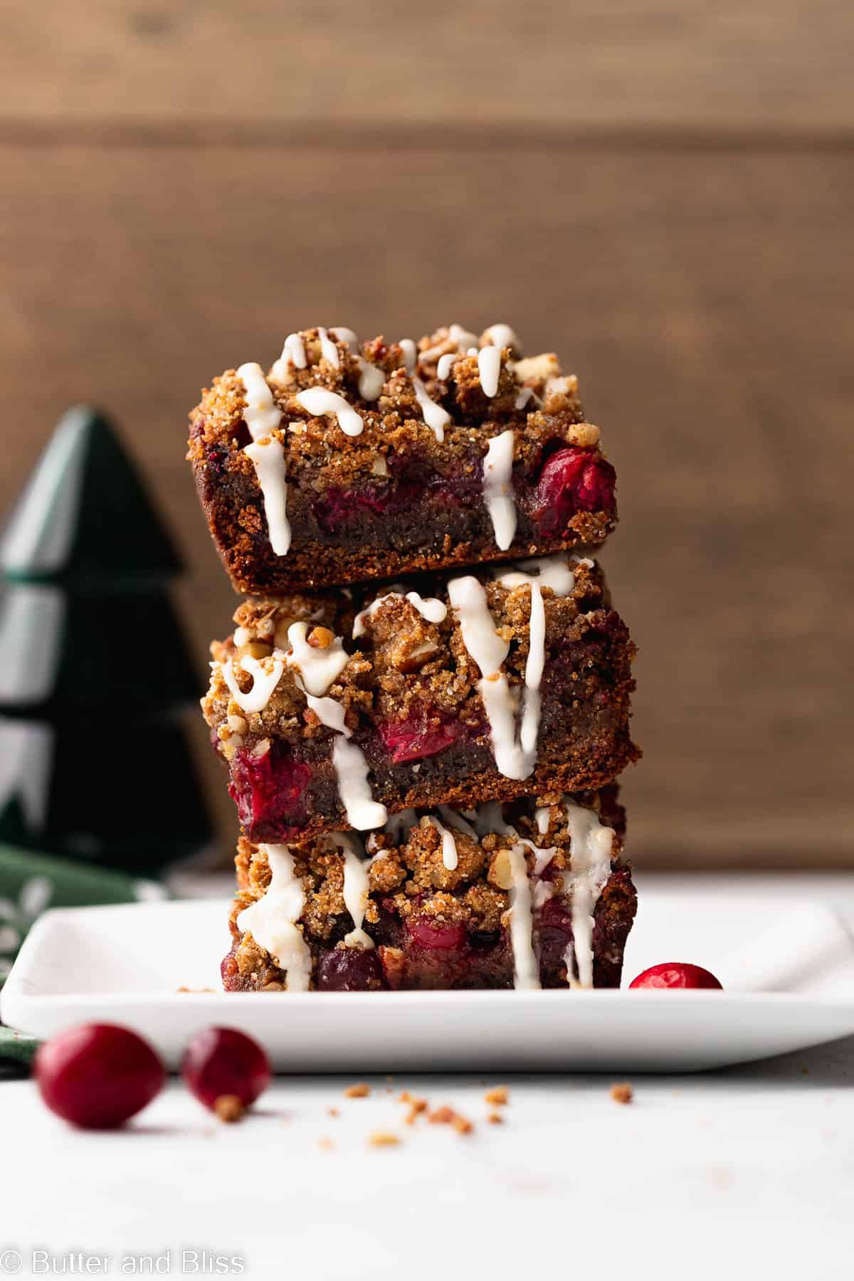 A pretty stack of cranberry gingerbread bars with orange icing on a white plate.