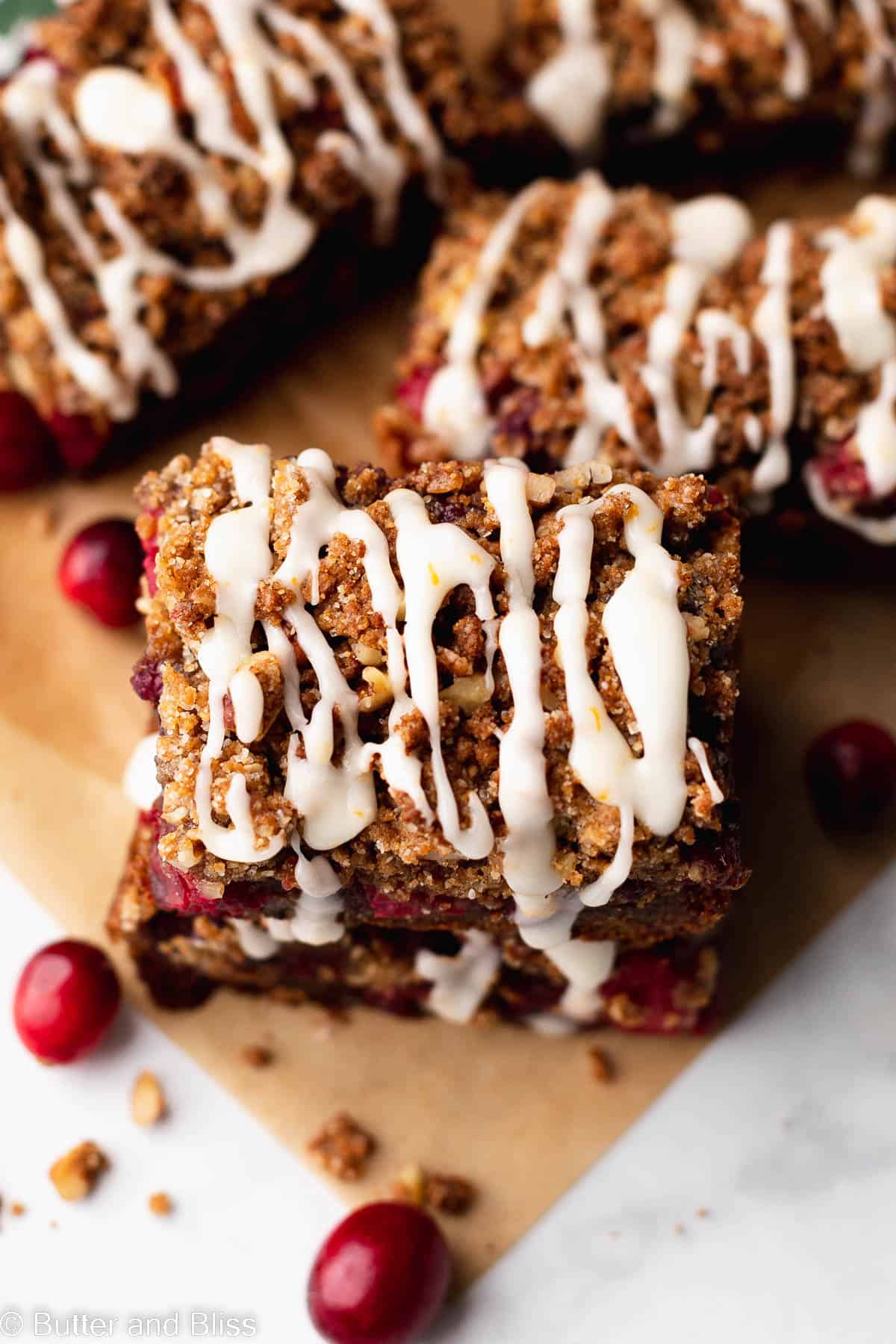 Gluten free gingerbread cranberry bars with orange icing arrange on a table.