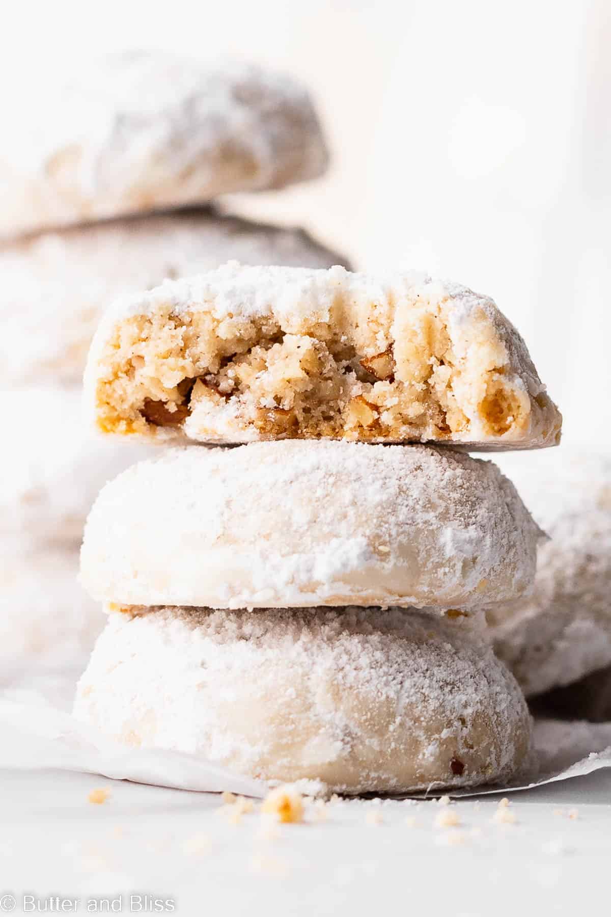 Close up on a stack of gluten free snowball cookies with a bite out of one.