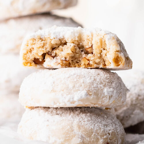 Close up on a stack of gluten free snowball cookies with a bite out of one.