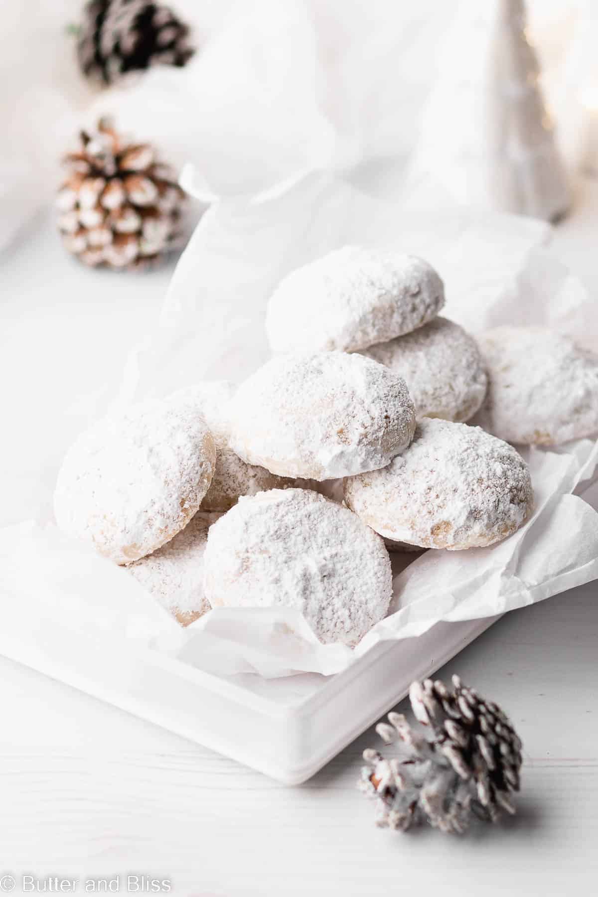 A stack of gluten free pecan snowball cookies set in a white cookie tray.