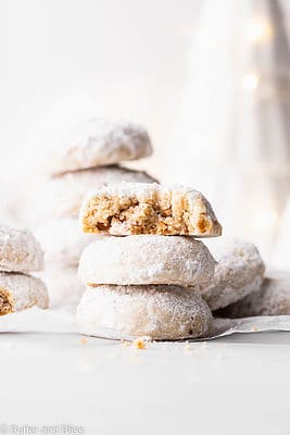 A short stack of gluten free snowball cookies with a bite out of one.