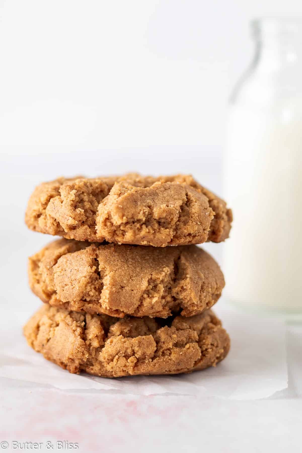 A stack of flourless peanut butter cookies set next to a glass of milk.