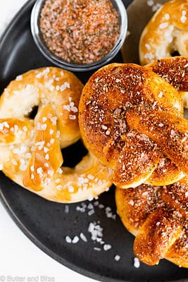 Seasoned homemade pretzels stacked on a black plate.