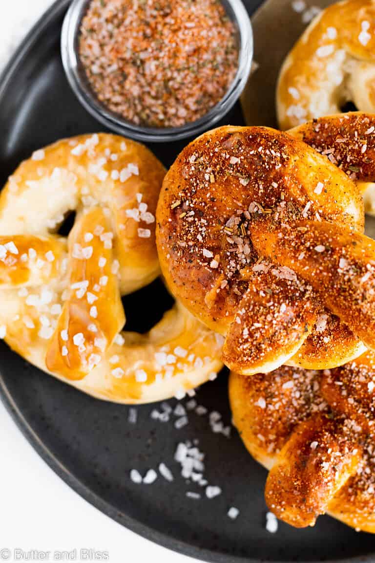 Seasoned homemade pretzels stacked on a black plate.