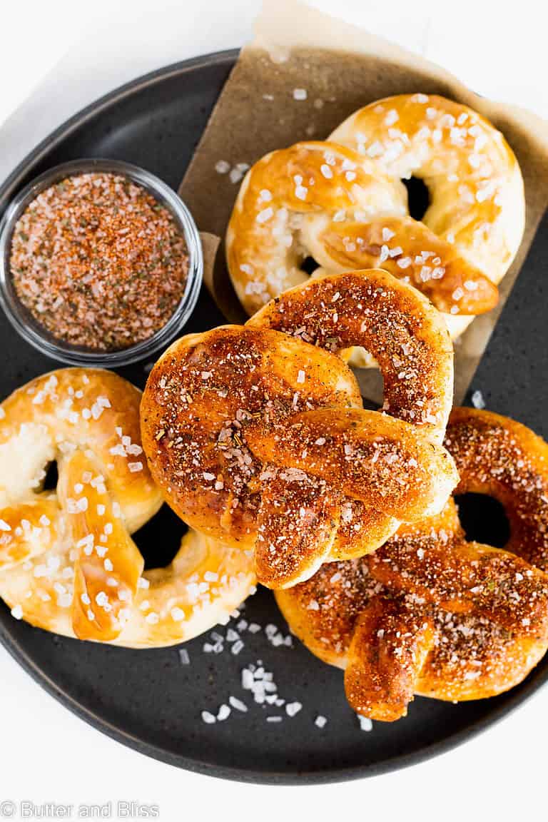 Soft baked pretzels sprinkled with zesty seasoning on a dark plate.