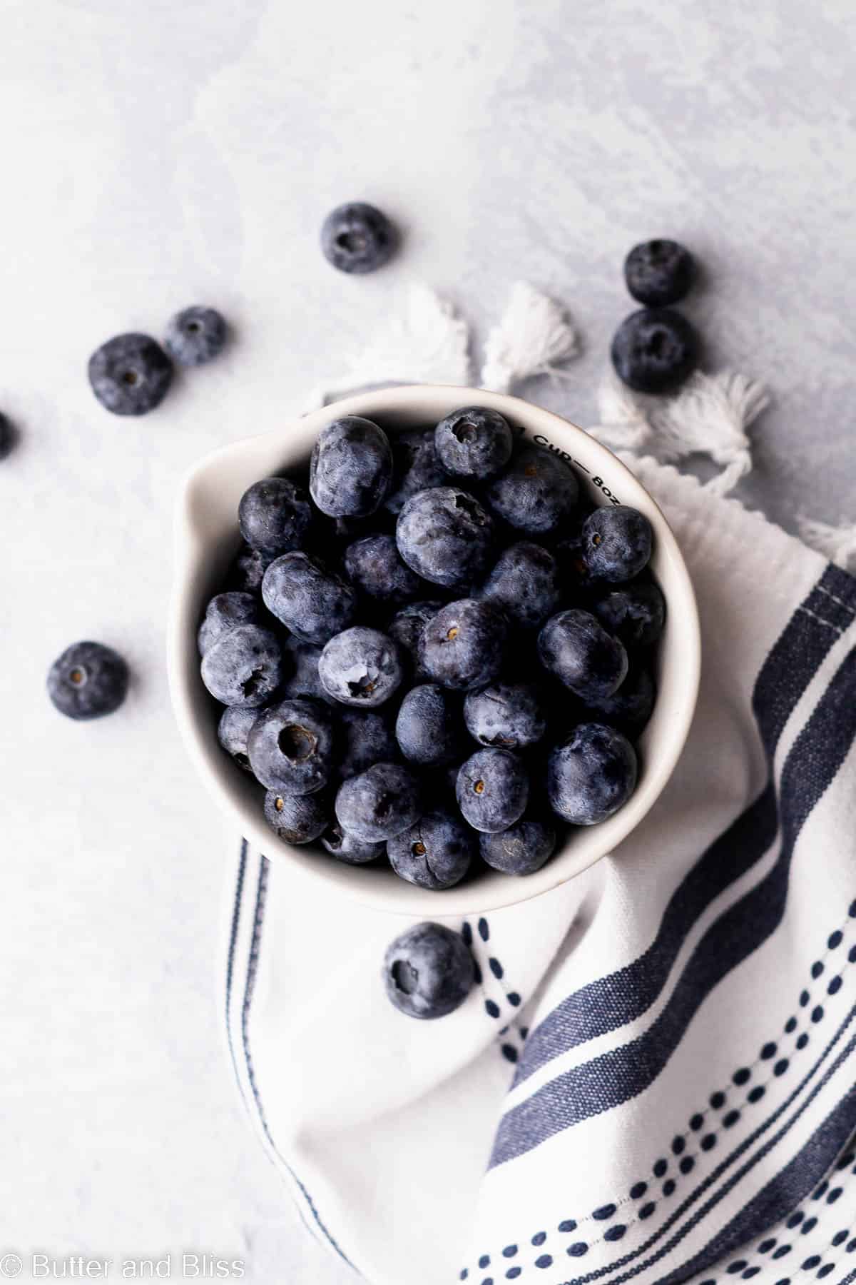 A bowl of fresh berries set on a blue table.