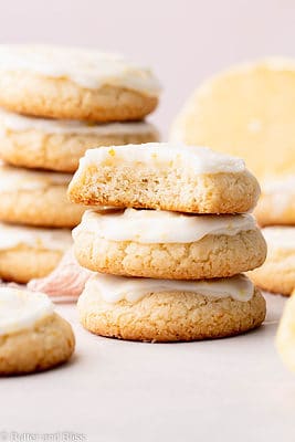 A short stack of glazed lemon drop shortbread cookies with a bite out of one.
