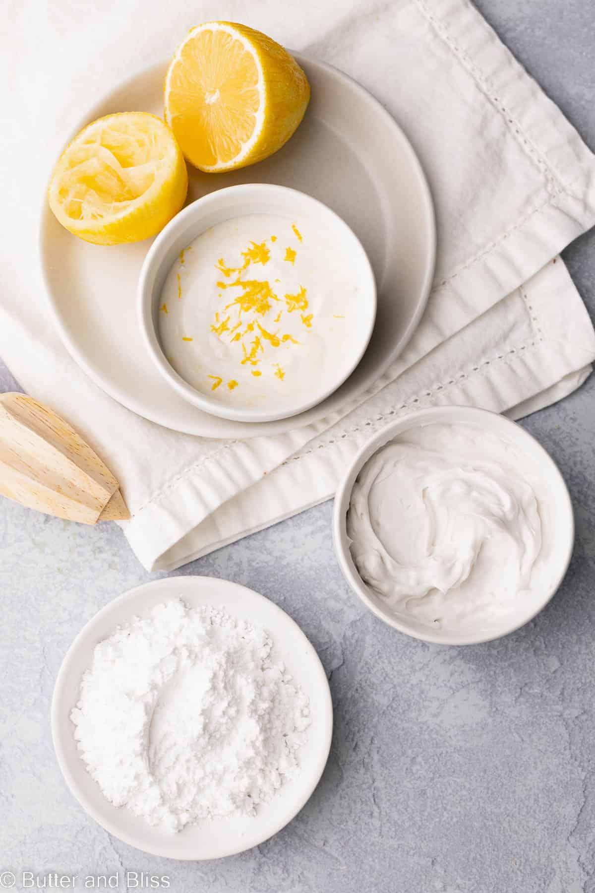Creamy lemon glaze ingredients in small white bowls arranged on a table.