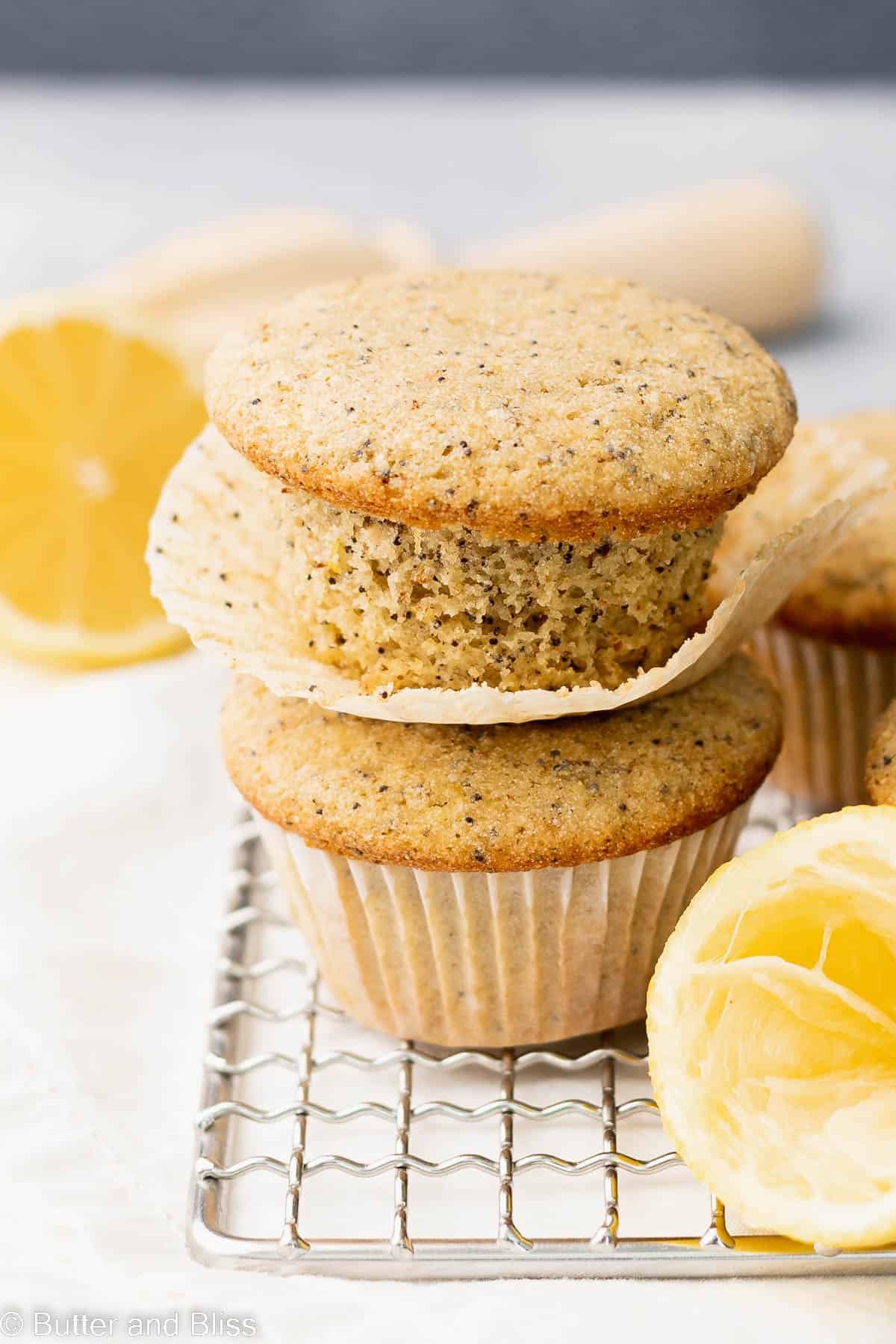 Two gluten free lemon poppyseed muffins stacked on a wire cooling rack.
