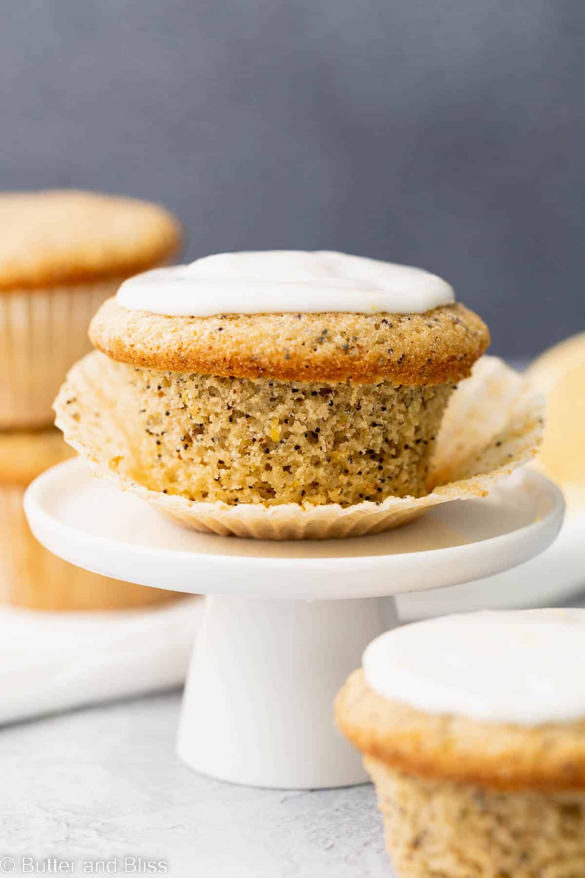 A single gluten free lemon breakfast muffin with lemon cream glaze set on a small cupcake stand.