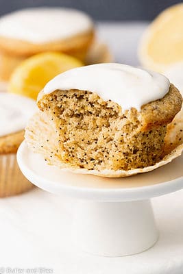 Close up bite shot of a super moist lemon breakfast muffin with a creamy glaze on a small cupcake stand.