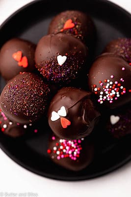 A plate of neatly stacked chocolate covered cake truffles.