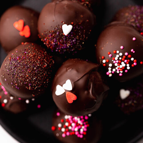 A plate of neatly stacked chocolate covered cake truffles.