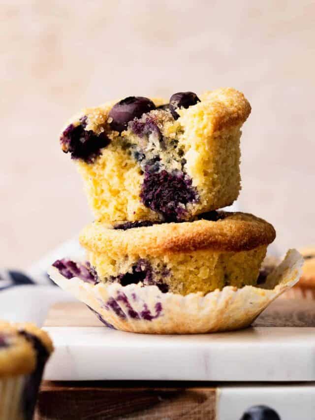 A bite shot of a fluffy gluten free blueberry muffin revealing tons of blueberries.