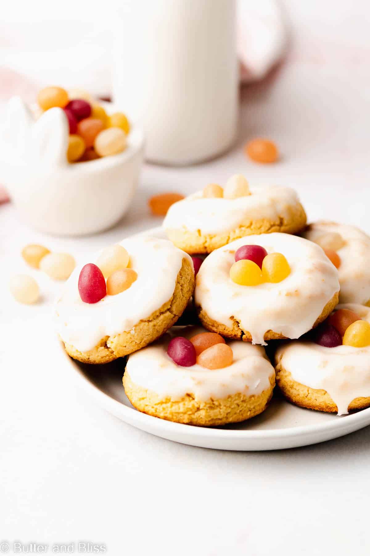 A plate of buttery soft gluten free jelly bean lemon cookies set on a table.