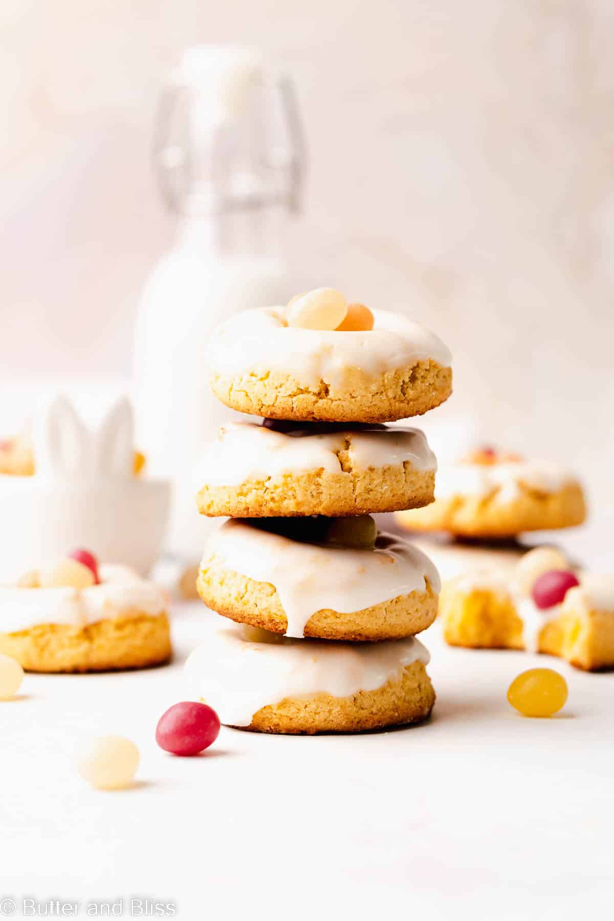 A sweet stack of easter cookies with a glass of milk on a table.