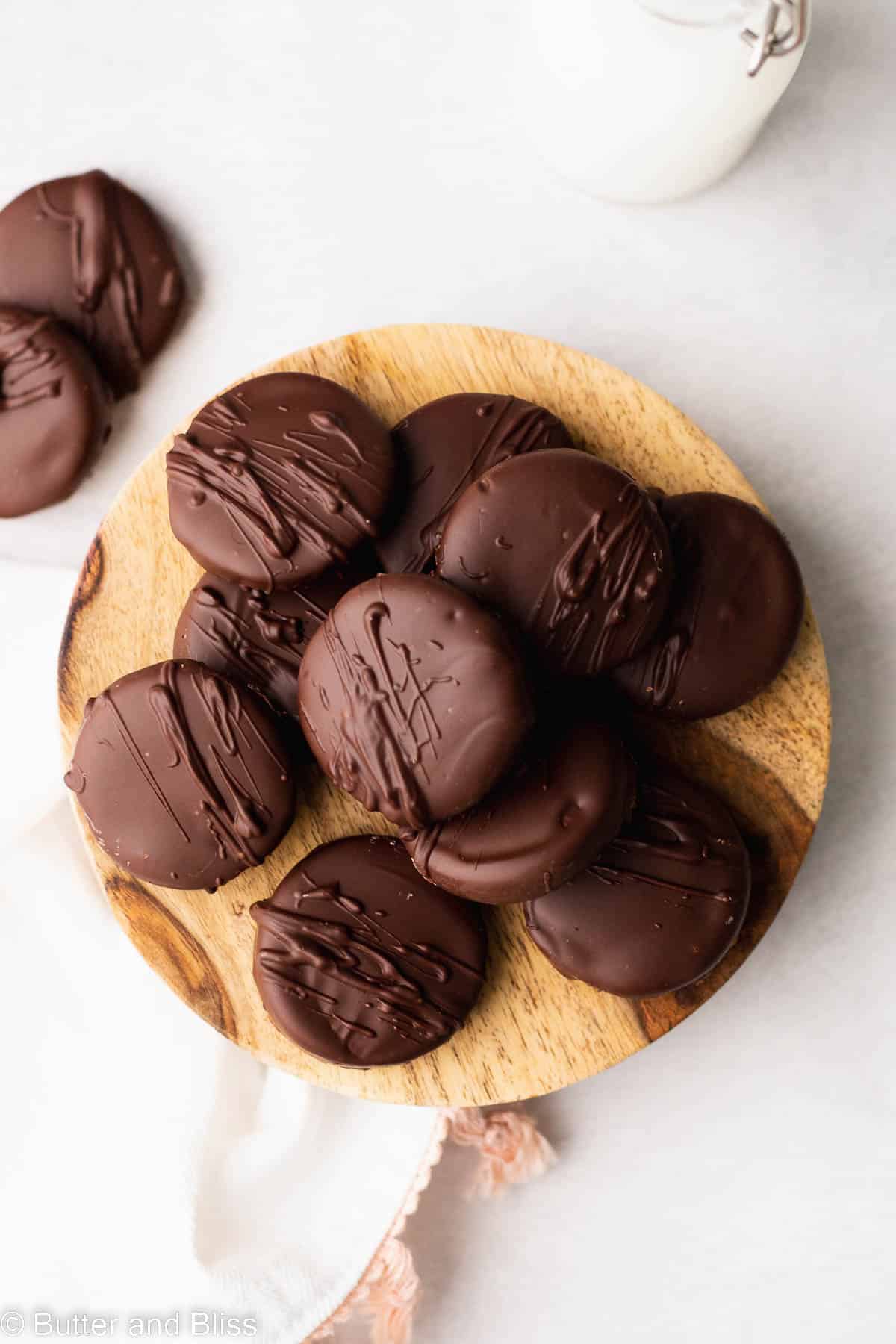 Small wooden plate full of gluten free chocolate covered chocolate cookies.