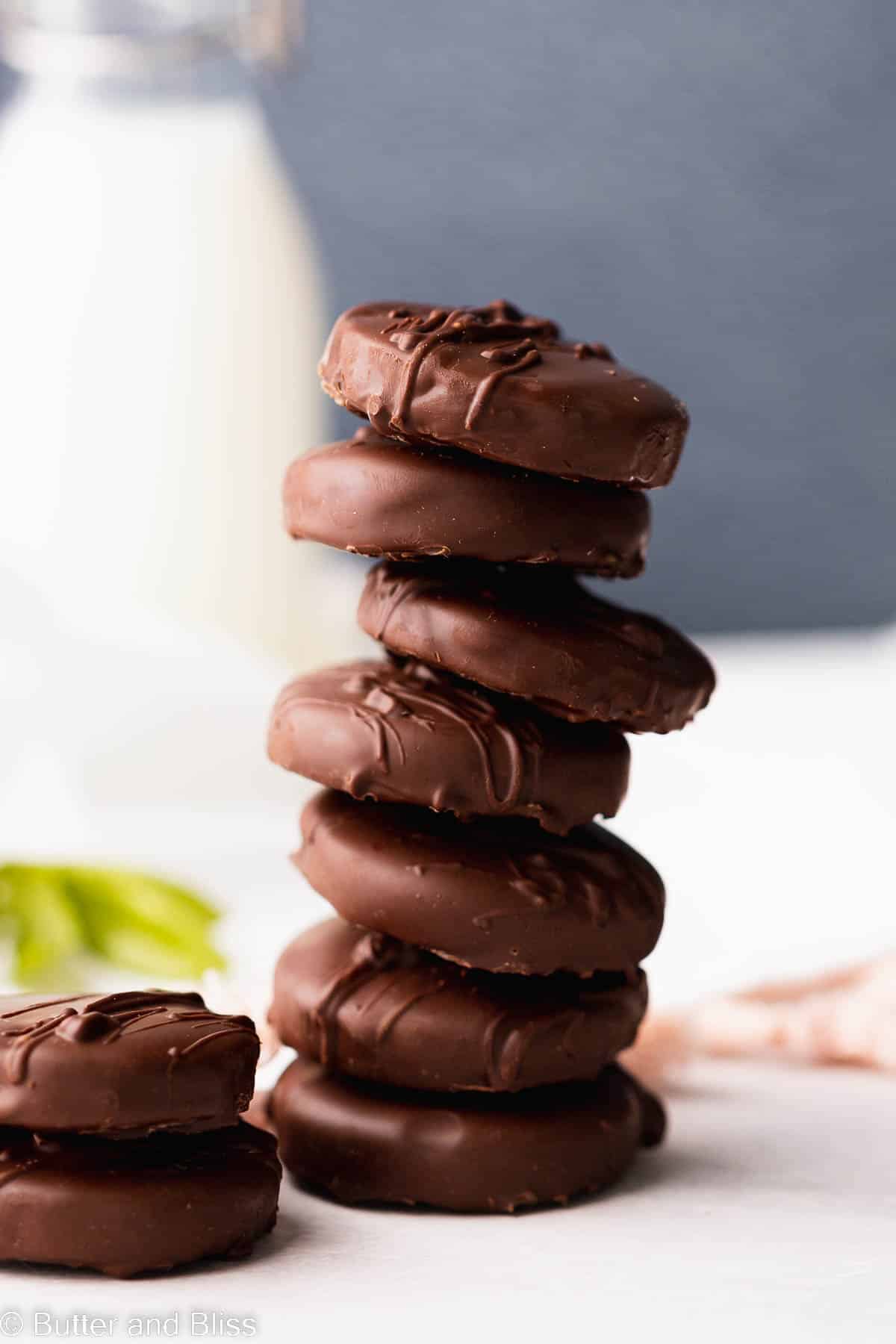 Tall stack of gluten free chocolate thin mint cookies set next to a glass of milk on a table.