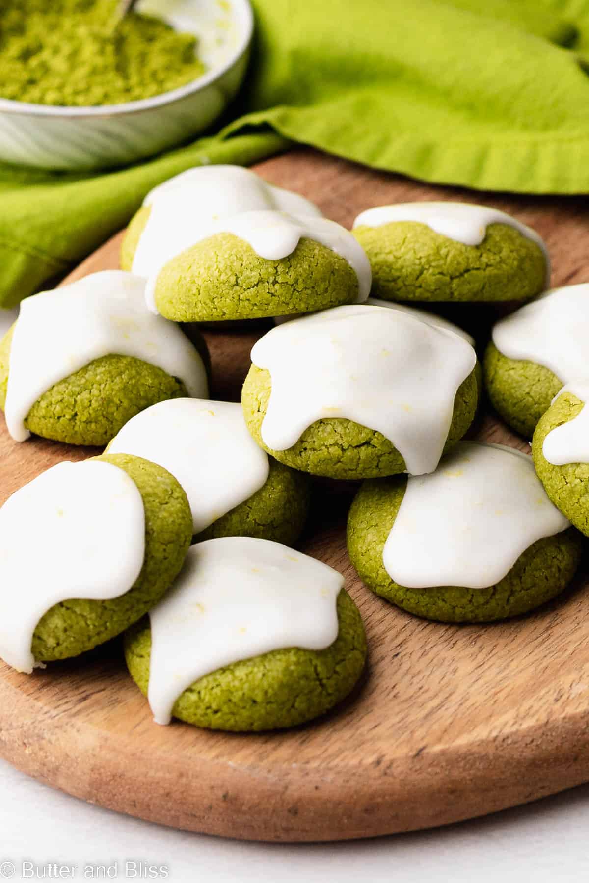 Gluten free matcha cookies with icing on a wooden tray.