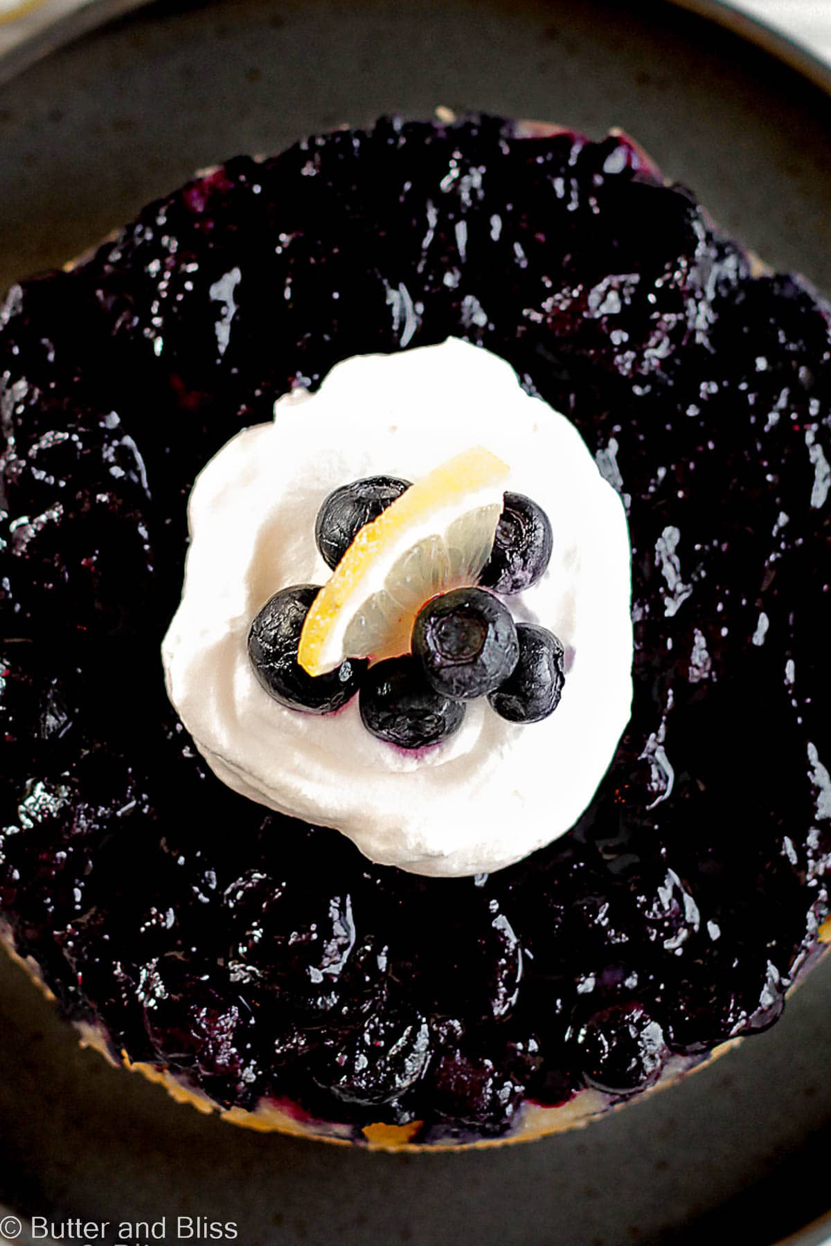 Looking down on a blueberry upside down cake topped with whipped cream.
