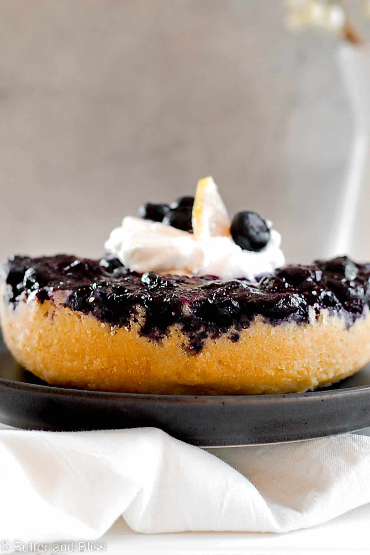Vibrant blueberry upside down cake on a dark plate.