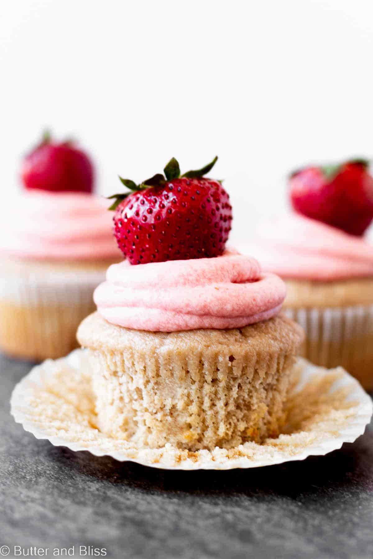 A double strawberry cupcake with the liner peeled back.