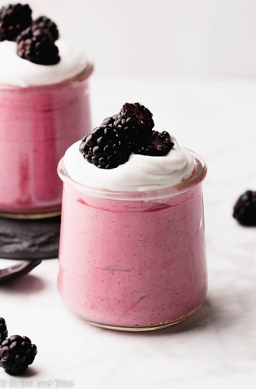 Super creamy and bright blackberry mousse in a serving glass set on a table.