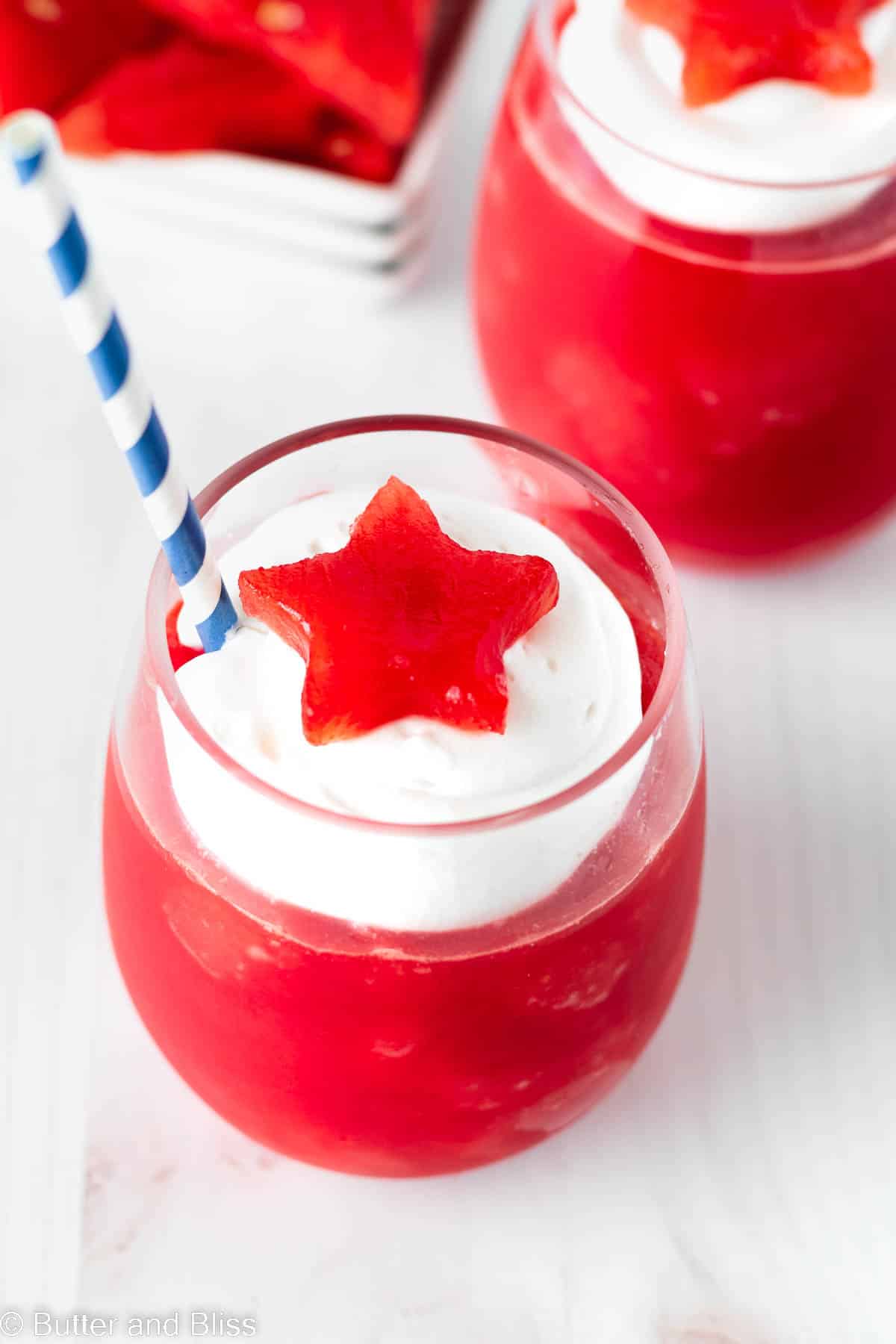 Watermelon slushie with creamy topping and watermelon star in a clear glass.