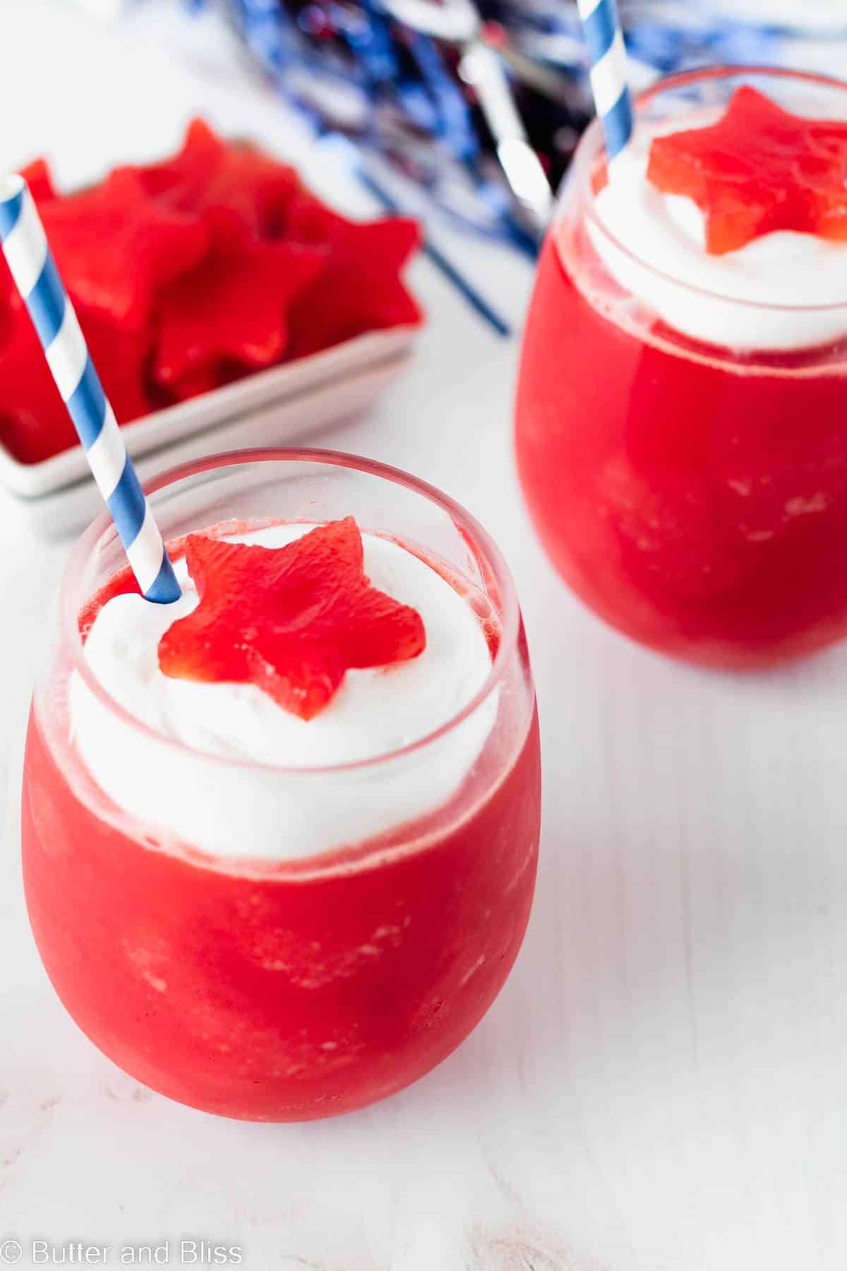 Two creamy watermelon slushies on a picnic table topped with watermelon stars.