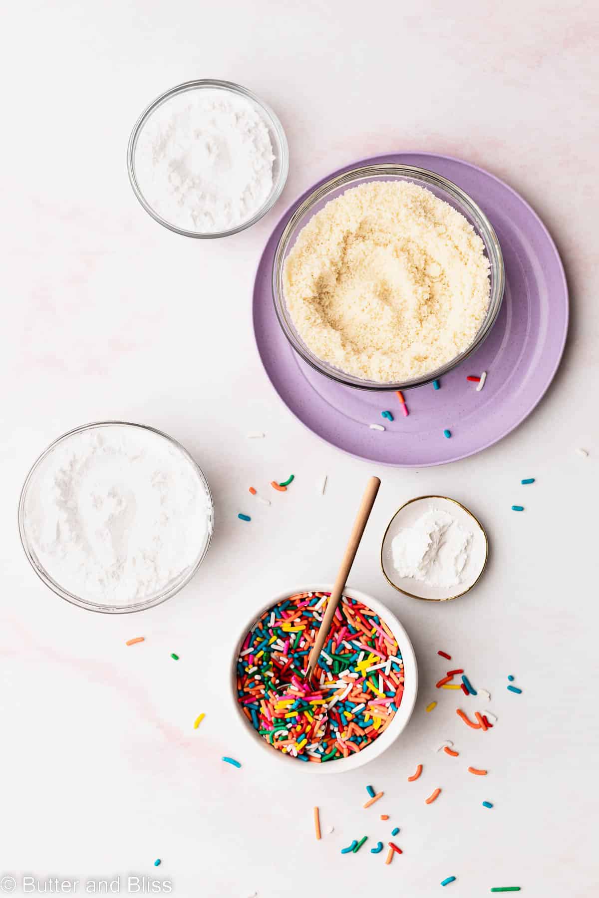 Dry ingredients arranged on a table in little bowls for gluten free vanilla cupcakes.