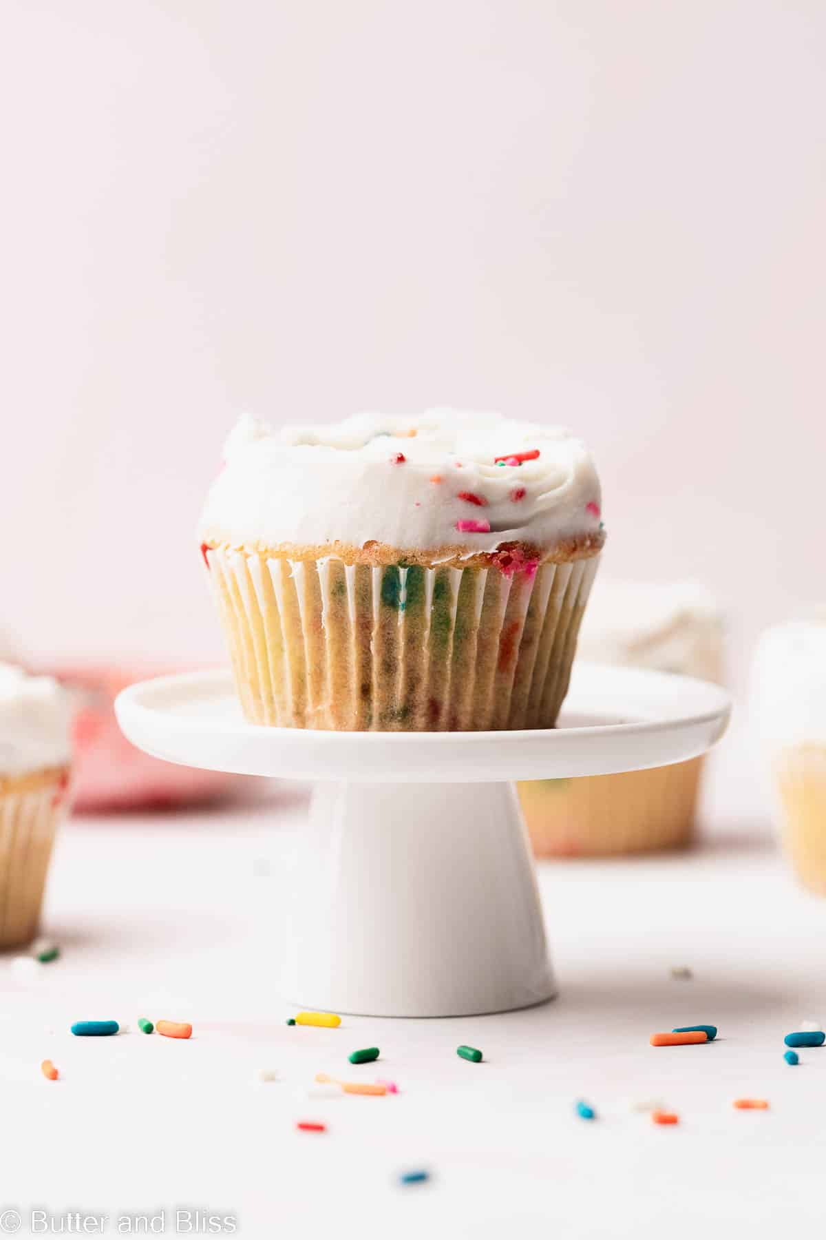 The sweetest little funfetti cupcake with butter free funfetti frosting on a mini white cake stand.