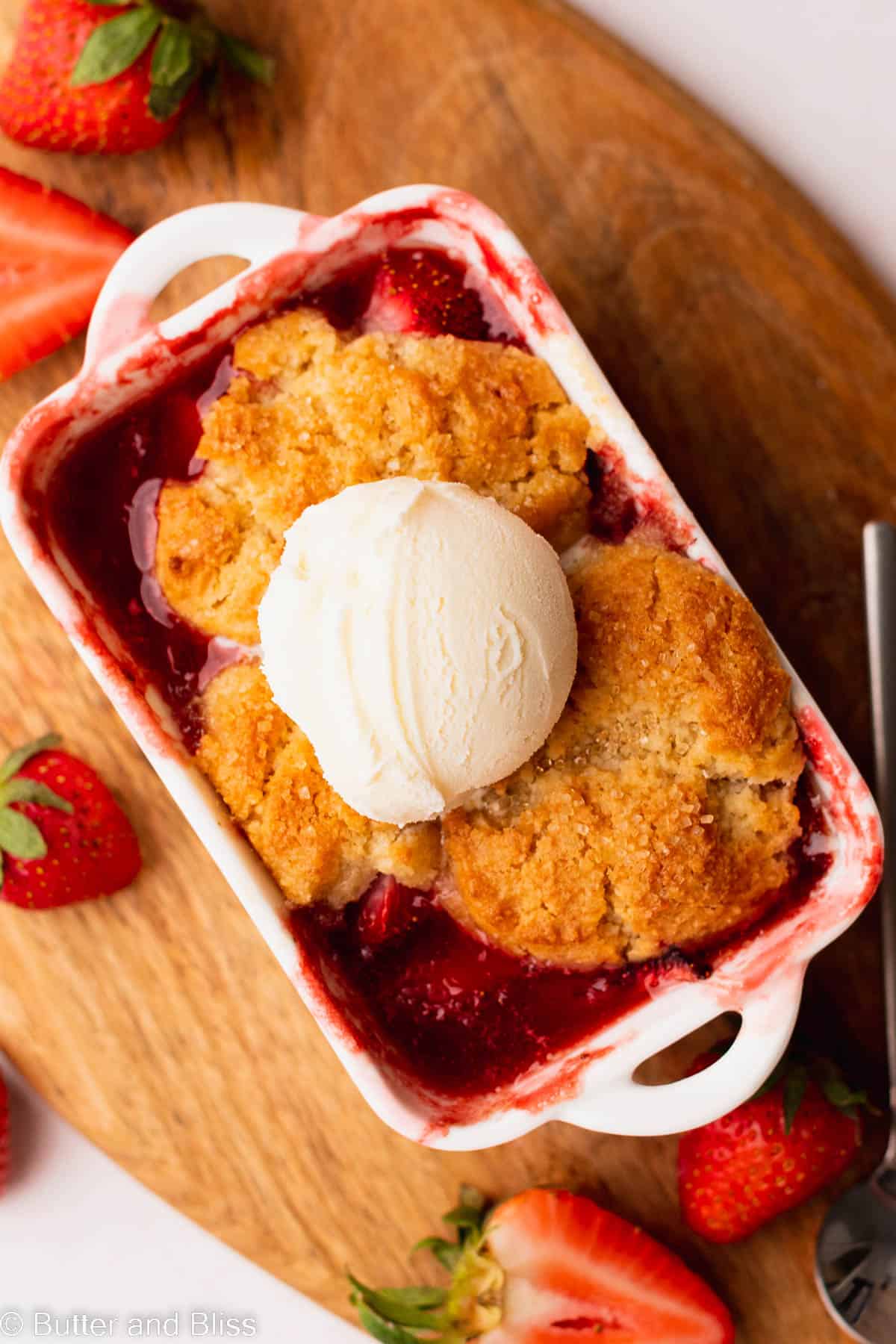 A single mini gluten free strawberry in a baking dish topped with ice cream.